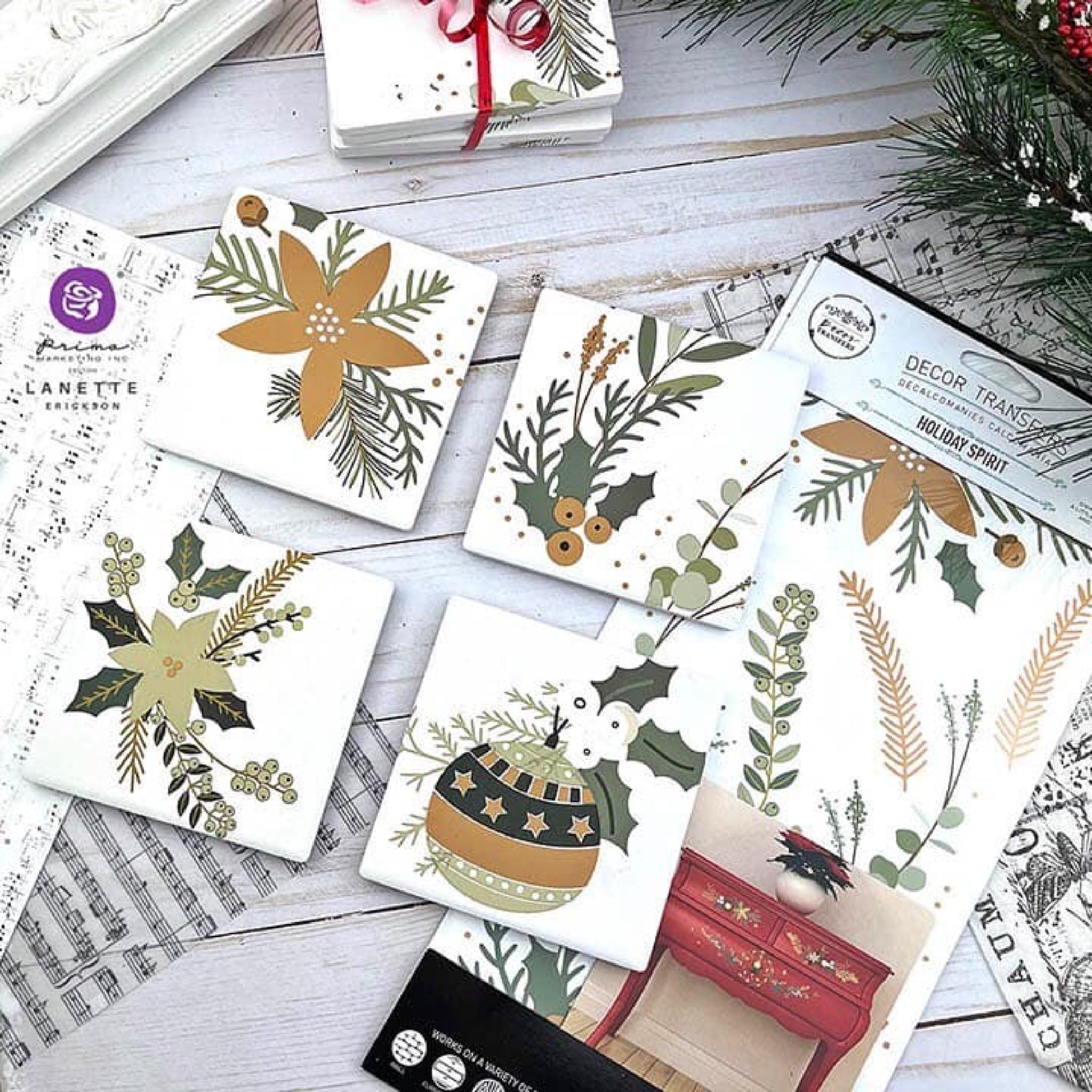 Four white tiles created by Lanette Erickson features pieces of ReDesign with Prima's Holiday Spirit small transfer on them. The package of the transfer are under the 2 right tiles.