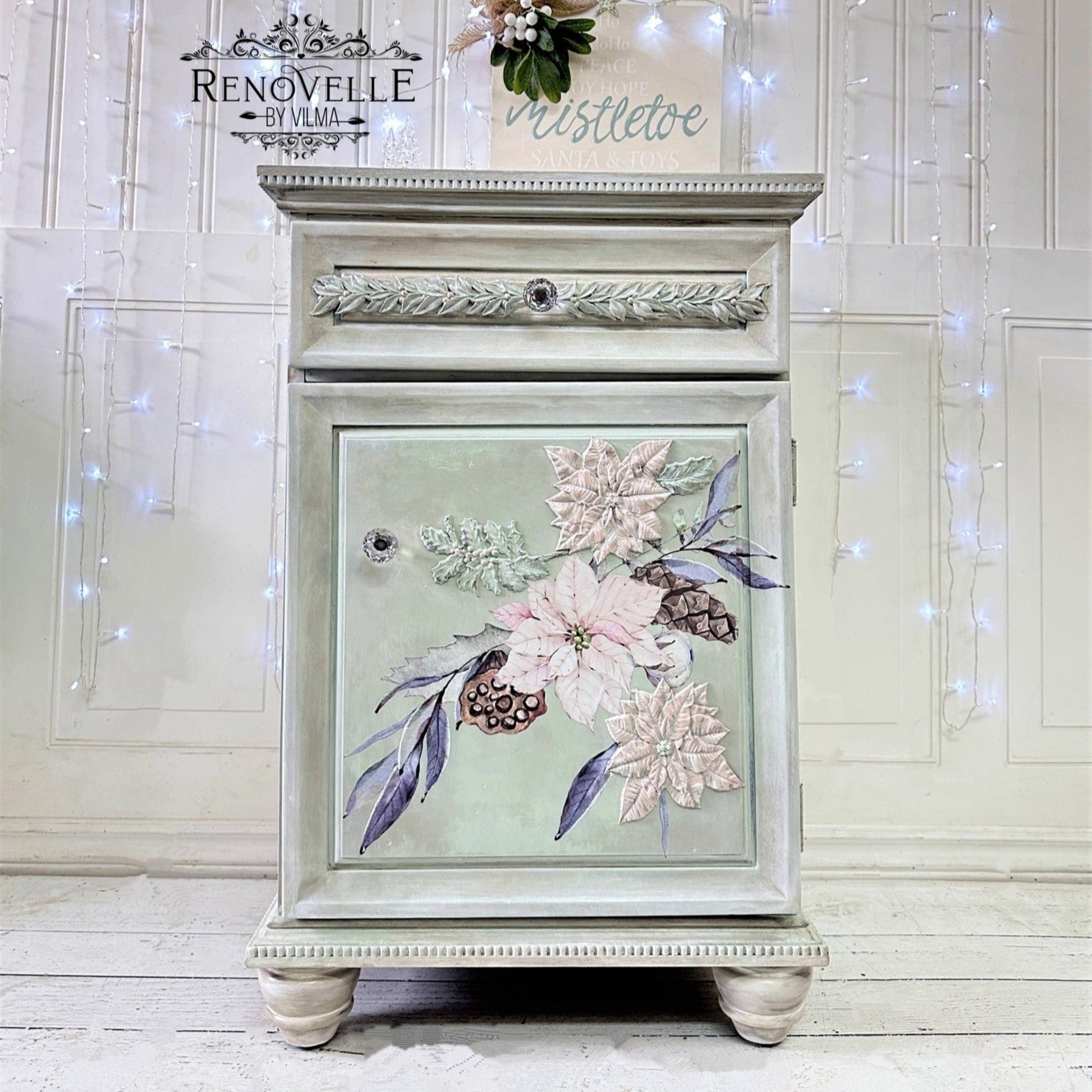 A vintage end table with storage refurbished by Renovelle by Vilma is painted pale green and features 2 ReDesign with Prima's Perfect Poinsettia silicone mold castings colored pale pink on the door.