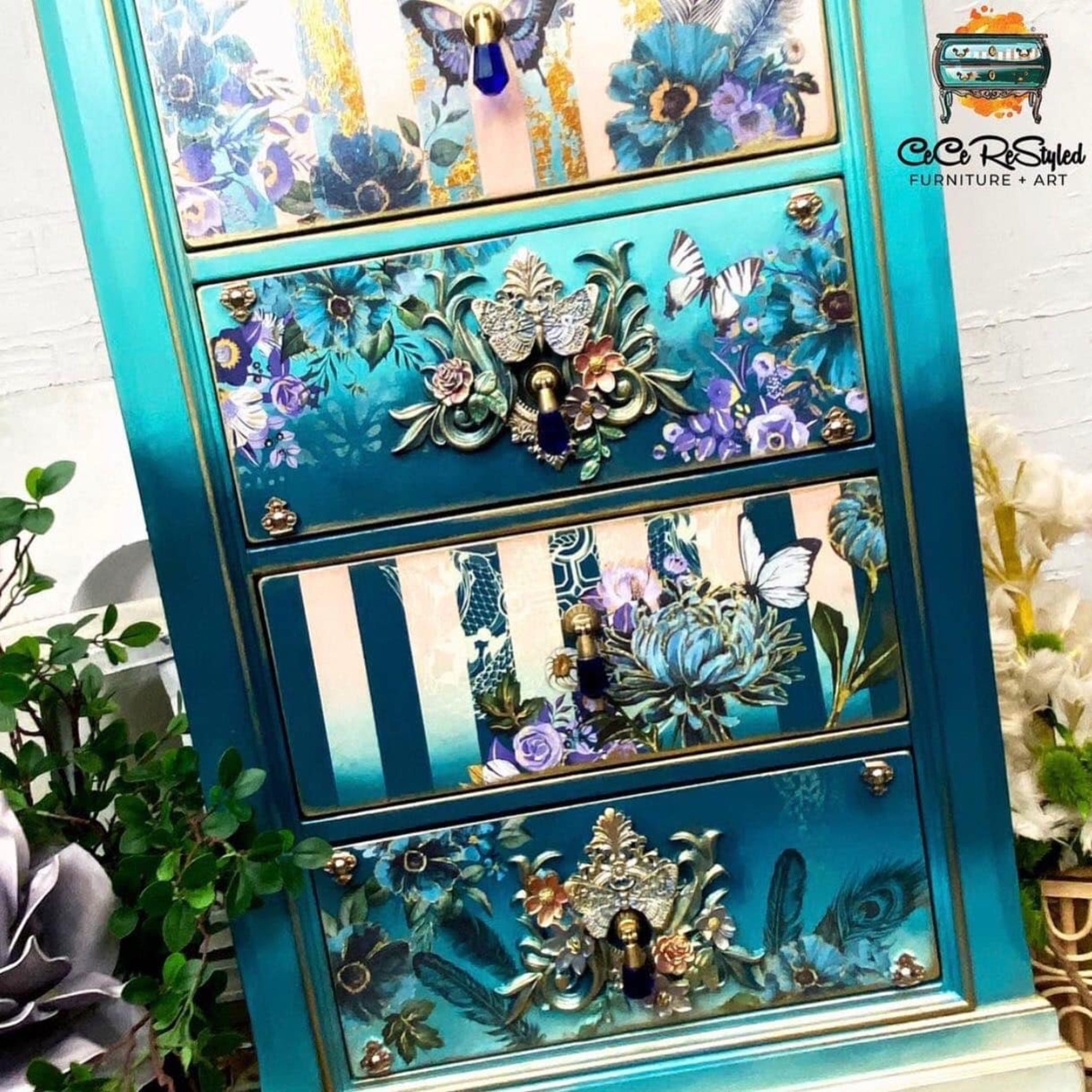 A close-up of a 6-drawer lingerie chest refurbished by CeCe ReStyled is painted an ombre blend of white down to dark teal and features ReDesign with Prima's Gilded Floral small transfer on some of its drawers along with a few other floral transfers and silicone mould castings.