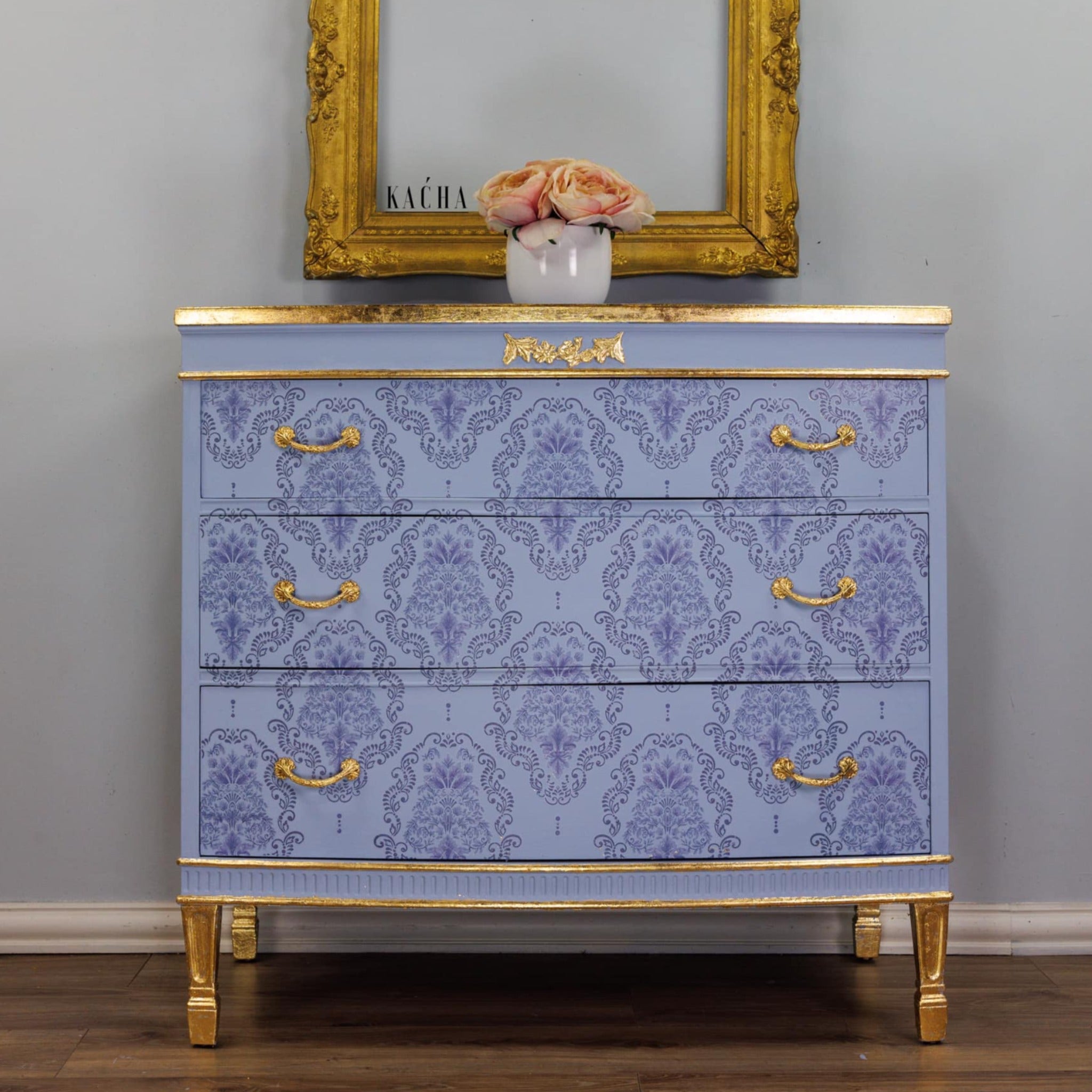 A dresser refurbished by Kacha is painted light blue with gold accents and features the Kacha Dana Damask trasnfer on its drawers.