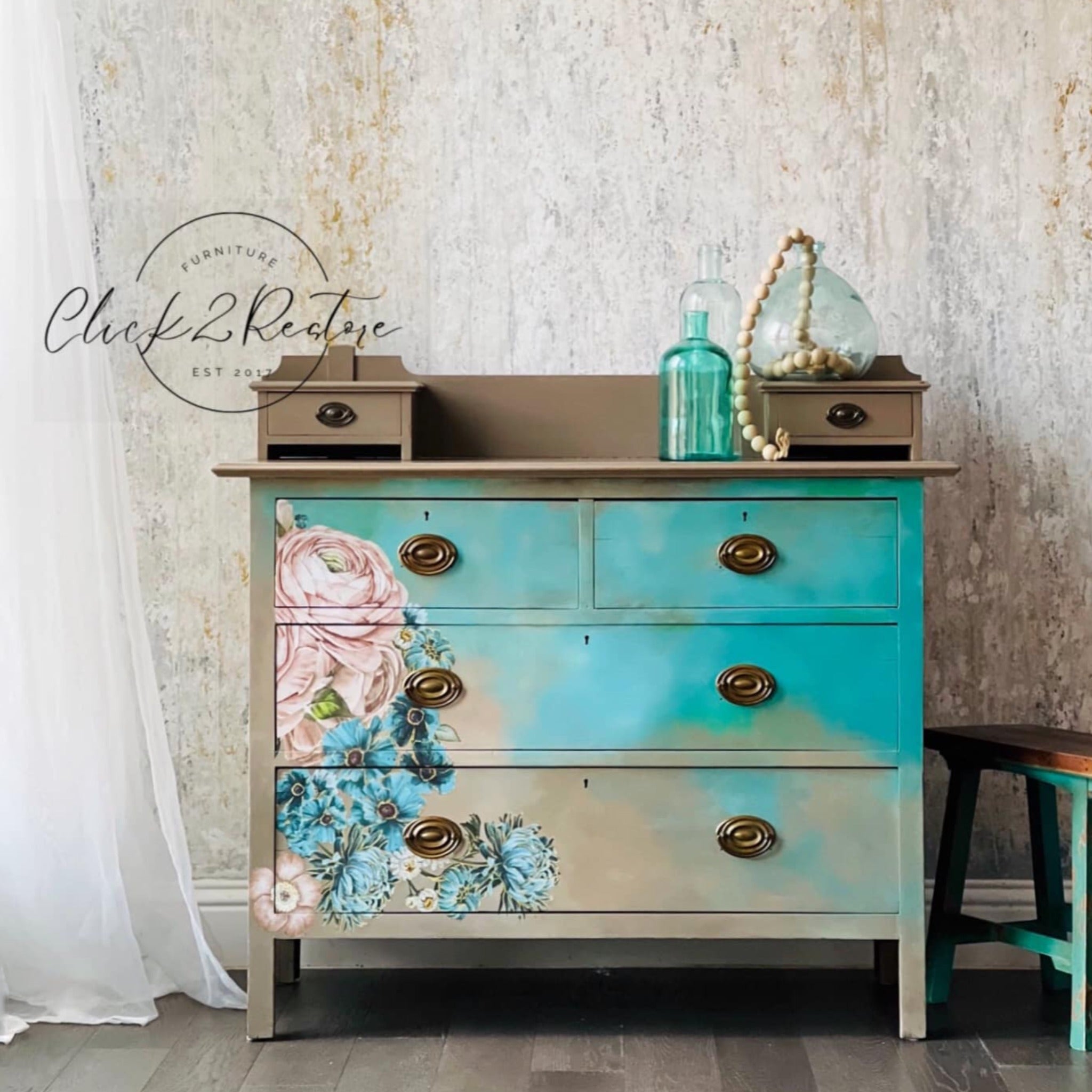 A 4-drawer dresser refurbished by Click 2 Restore is painted a blend of light and medium tan and bright teal and features ReDesign with Prima's Gilded Floral small transfer towards the bottom left corner of the dresser front.