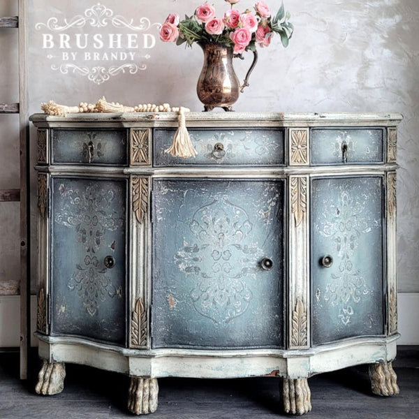 A vintage buffet table refurbished by Brushed by Brandy is painted a blend of light and navy blue with distressed white accents and features ReDesign with Prima's Kacha Dana Damask transfer on its drawers and doors.