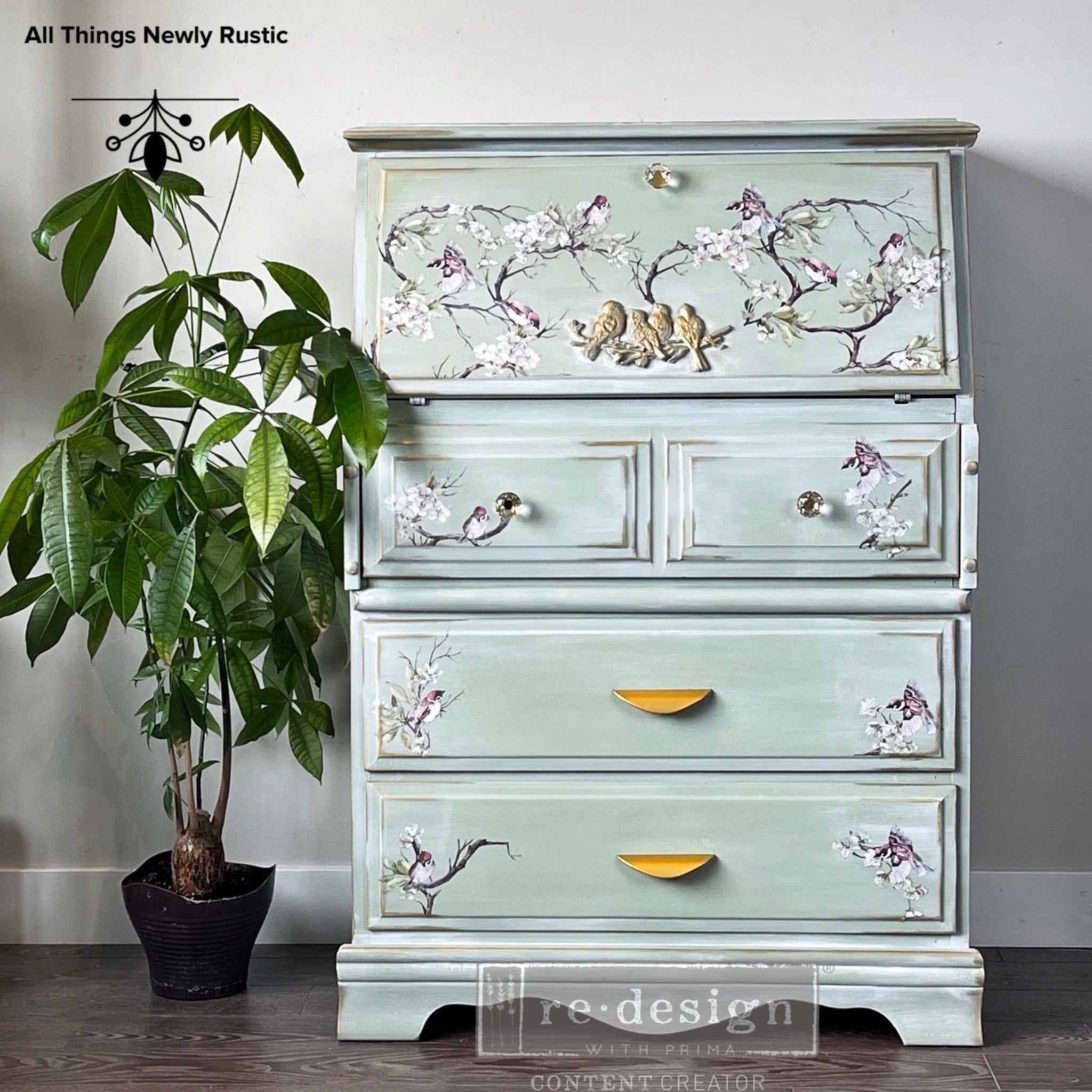 A vintage secretary's desk refurbished by All Things Newly Rustic is painted pale seafoam green and features ReDesign with Prima's Blossom Flight transfer on it.