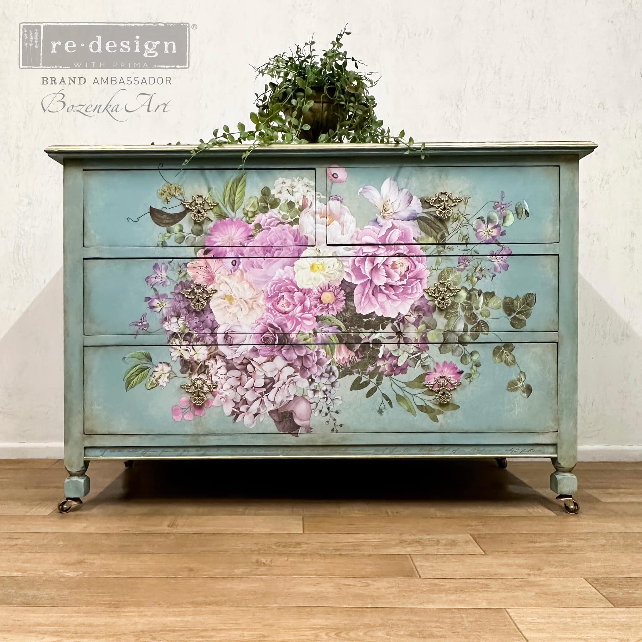 A vintage dresser refurbished by Bozenka Art is painted light teal blue and features ReDesign with Prima's Kacha Morning Purple transfer in the center of its drawers.