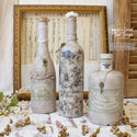 Rustic bottles refurbished by One of a Second Kind Designs are painted ceramic grey and feature ReDesign with Prima's Wild Gardens Small H2O transfer on the middle bottle.