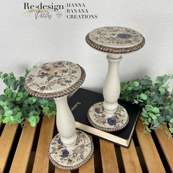 Candle holders refurbished by Hanna Banana Creations are painted white with bronze accents and feature ReDesign with Prima's Wild Garden Small H2O transfer on them.