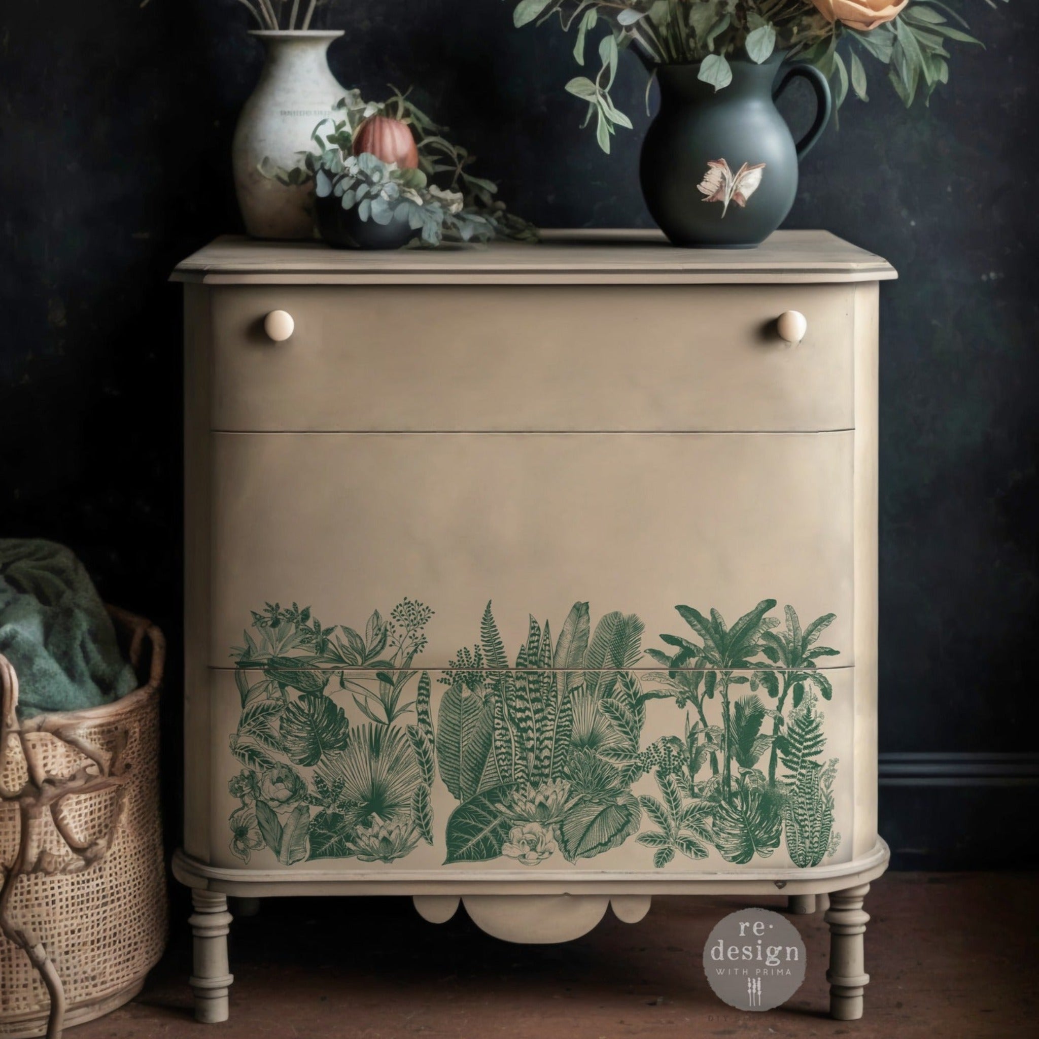 A small dresser is painted light beige and features ReDesign with Prima's Magic Jungle small transfer on the bottom drawer.