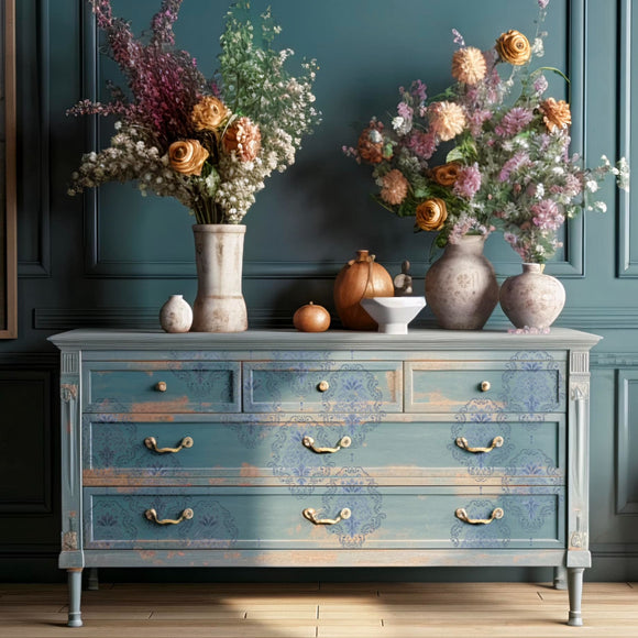 A large dresser is painted a distressed light blue and features ReDesign with Prima's Kacha Dana Damask transfer on its drawers.