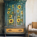 A vintage armoire is painted a weathered blue and features ReDesign with Prima's Sunflower transfer on its doors.
