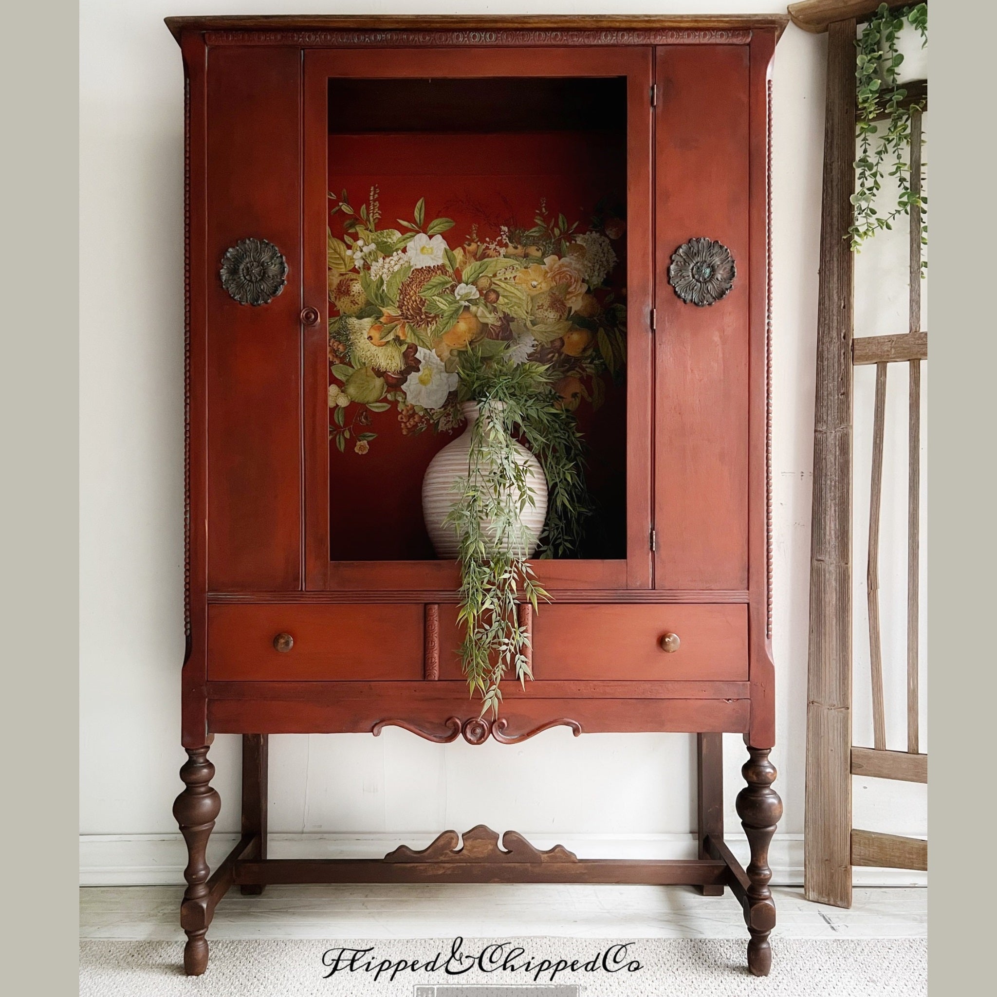 A vintage armoire refurbished by Flipped & Chipped Co. is painted a rust red and features ReDesign with Prima's Harvest Hues transferon the backboard inside the armoire.