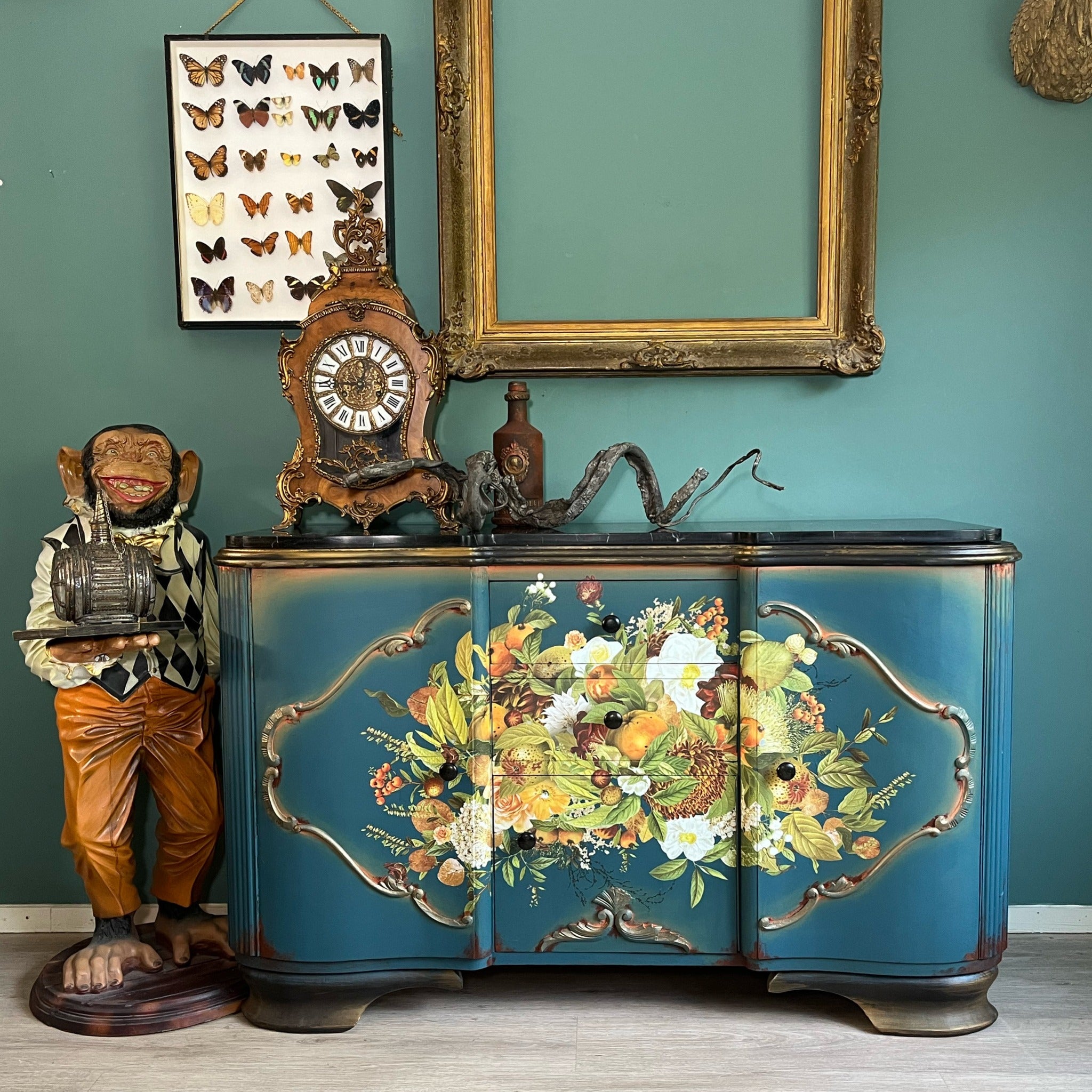 A vintage buffet table is painted blue with a black top and gold accents and features ReDesign with Prima's Harvest Hues transfer in the center of the front of the dresser.