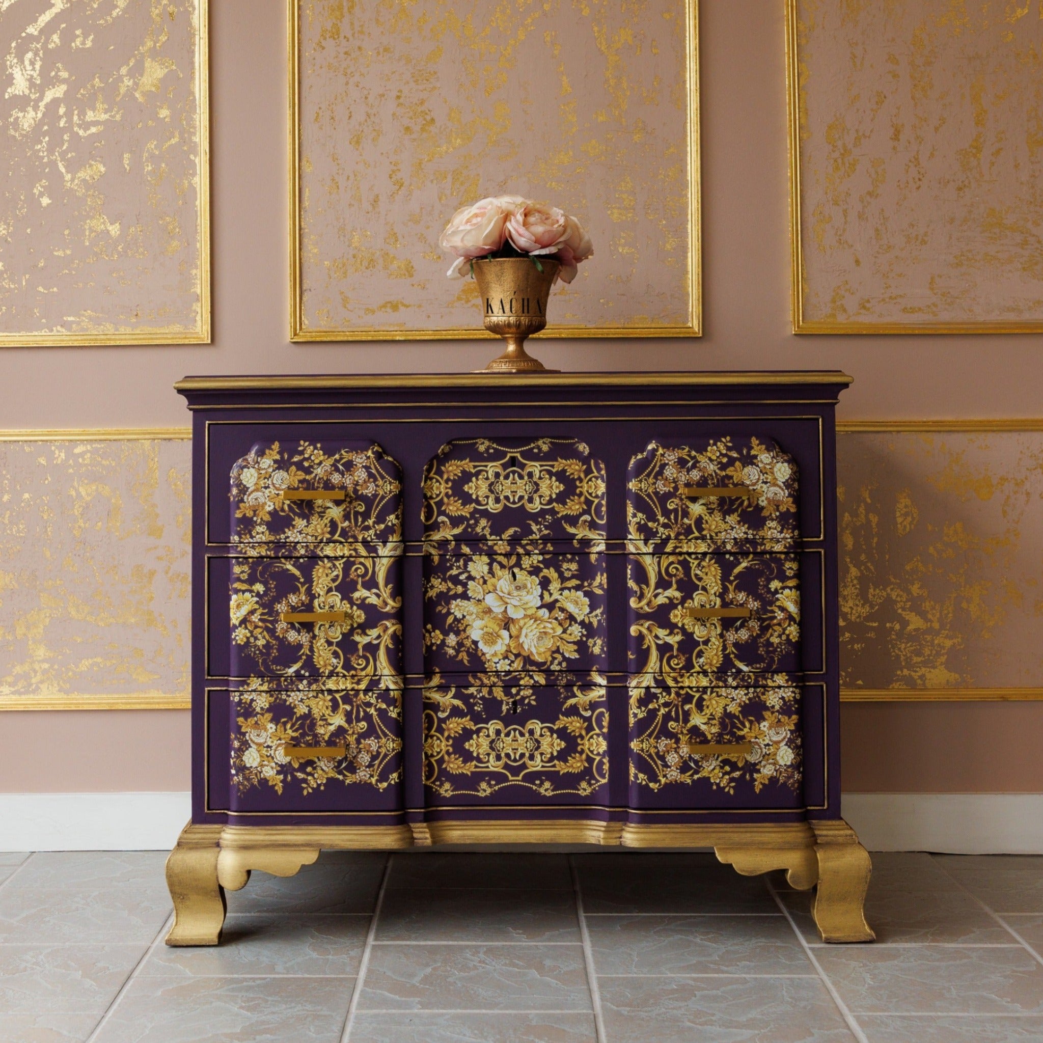 A vintage dresser refurbished by Kacha is painted a deep purple with gold accents and features ReDesign with Prima's Kacha Orleans on its drawers.