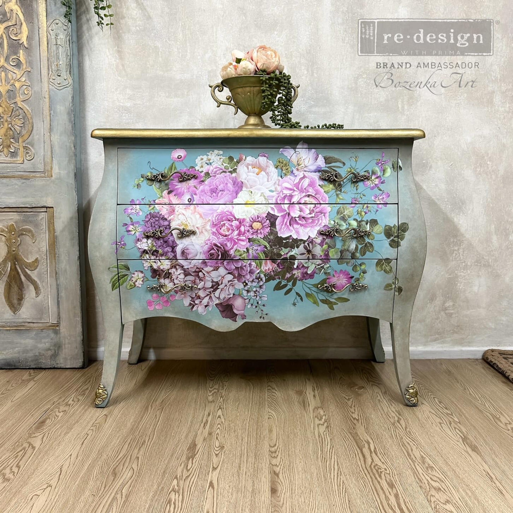 A vintage Bombay style dresser refurbished by Bozenka Art is painted a mottled grey with a sky blue ombre center and features ReDesign with Prima's Kacha Morning Purple transfer on its drawers.
