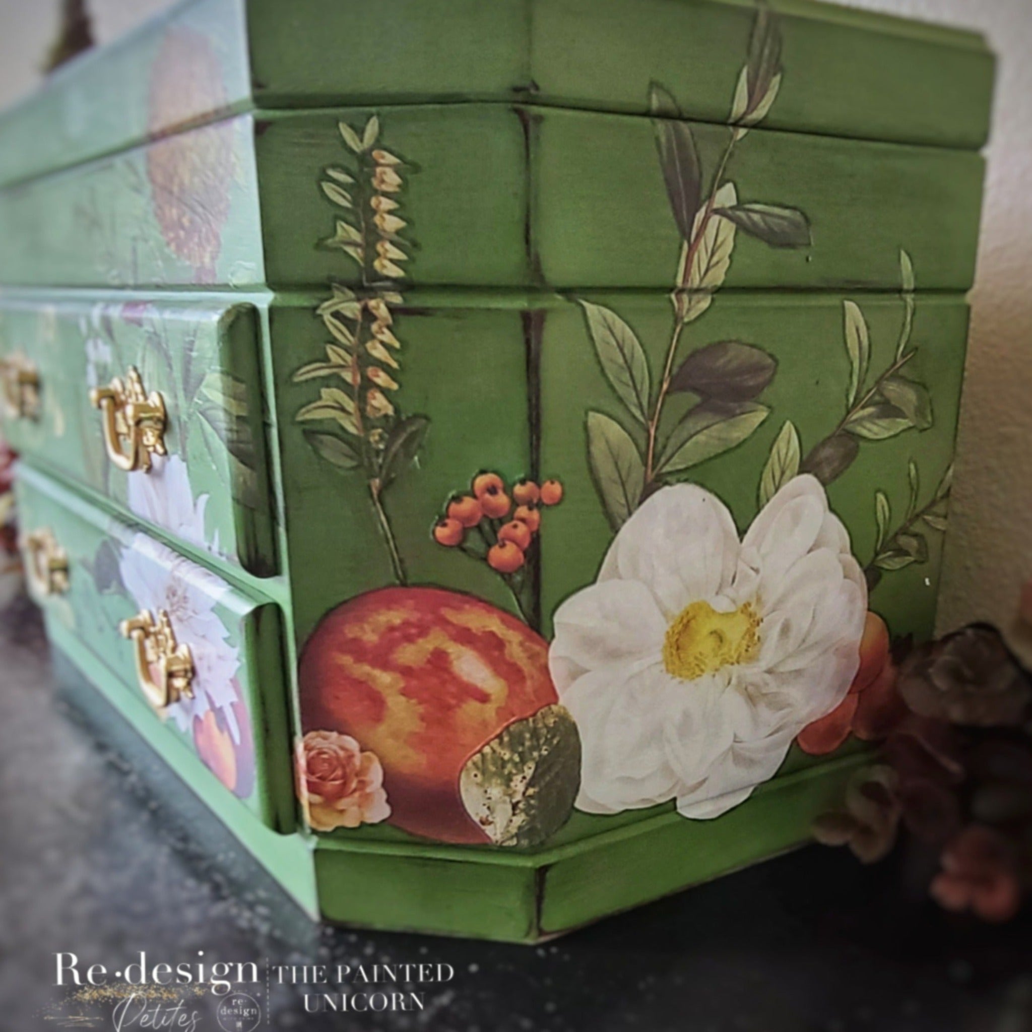 A corner angled view of a small vintage jewelry box refurbished by The Painted Unicorn is painted Spring green and features ReDesign with Prima's Seasonal Splendor small transfer on it.