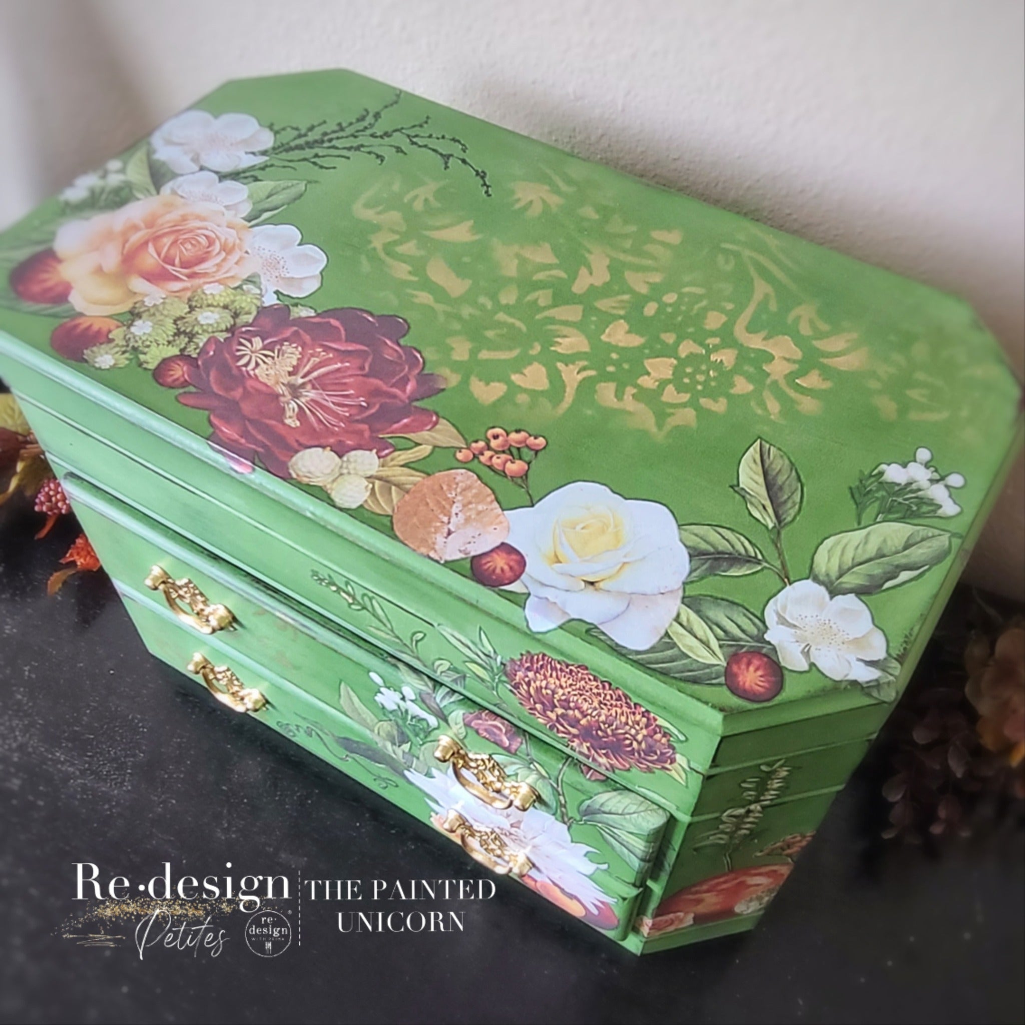 A top angled view of a small vintage jewelry box refurbished by The Painted Unicorn is painted Spring green and features ReDesign with Prima's Seasonal Splendor small transfer on it.