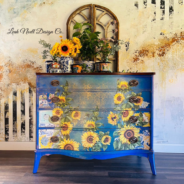 A vintage 4-drawer dresser refurbished by Leah Noell Design Co. is painted bright blue and features ReDesign with Prima's Sunflower transfer on its drawers.