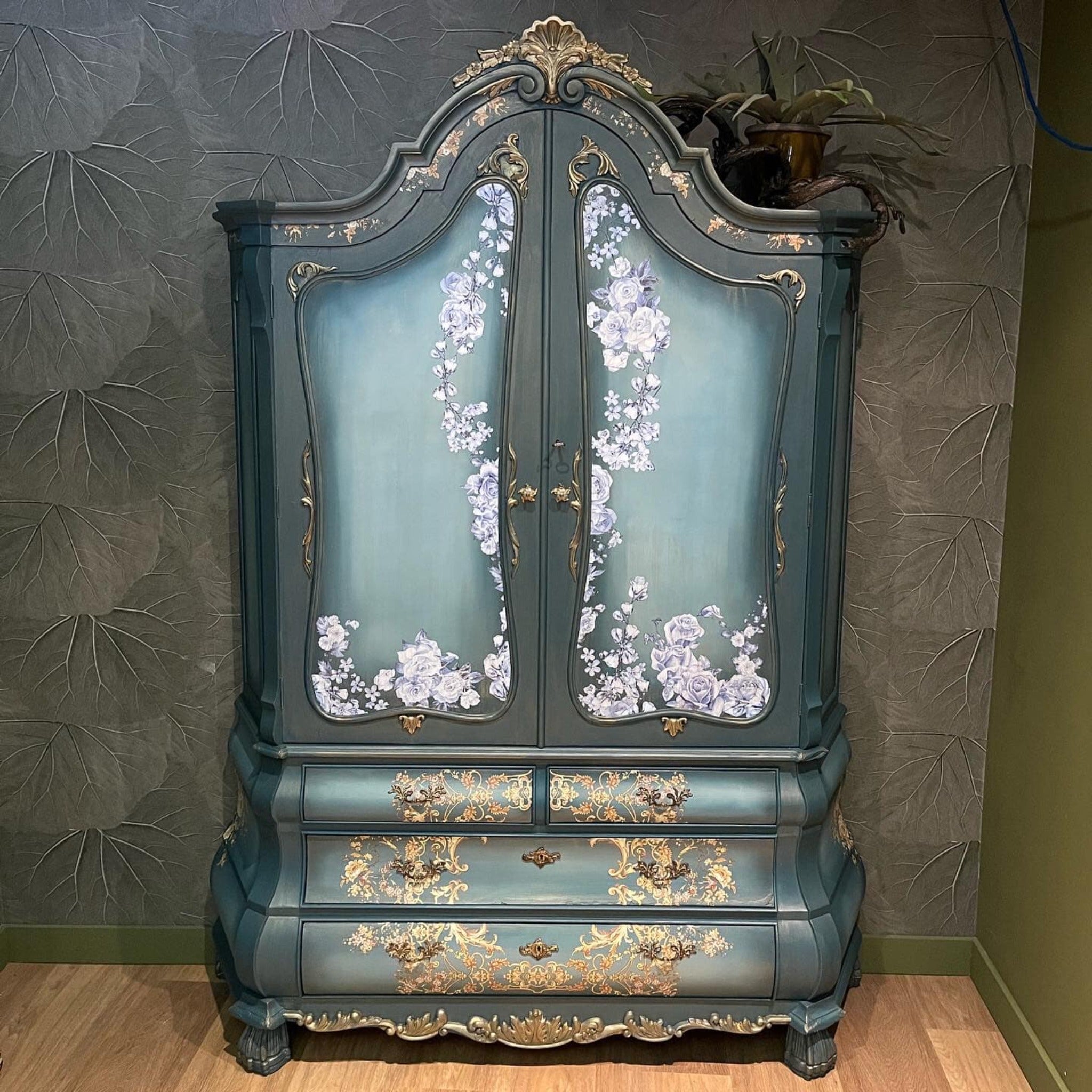 A vintage armoire refurbished by Stylish Interior is painted a metallic muted blue with a lighter blue ombre center on the doors and features ReDesign with Prima's Kacha Orleans transfer on its drawers.