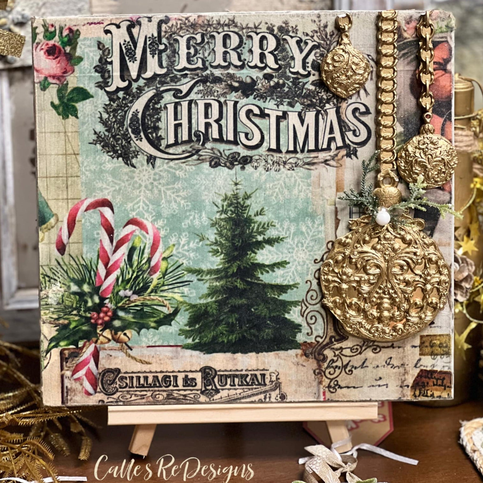 A small square canvas on a little canvas stand created by Calle's ReDesigns features the Merry Christmas design from ReDesign with Prima's Holly Jolly Hideaway 3 pack tissue papers.