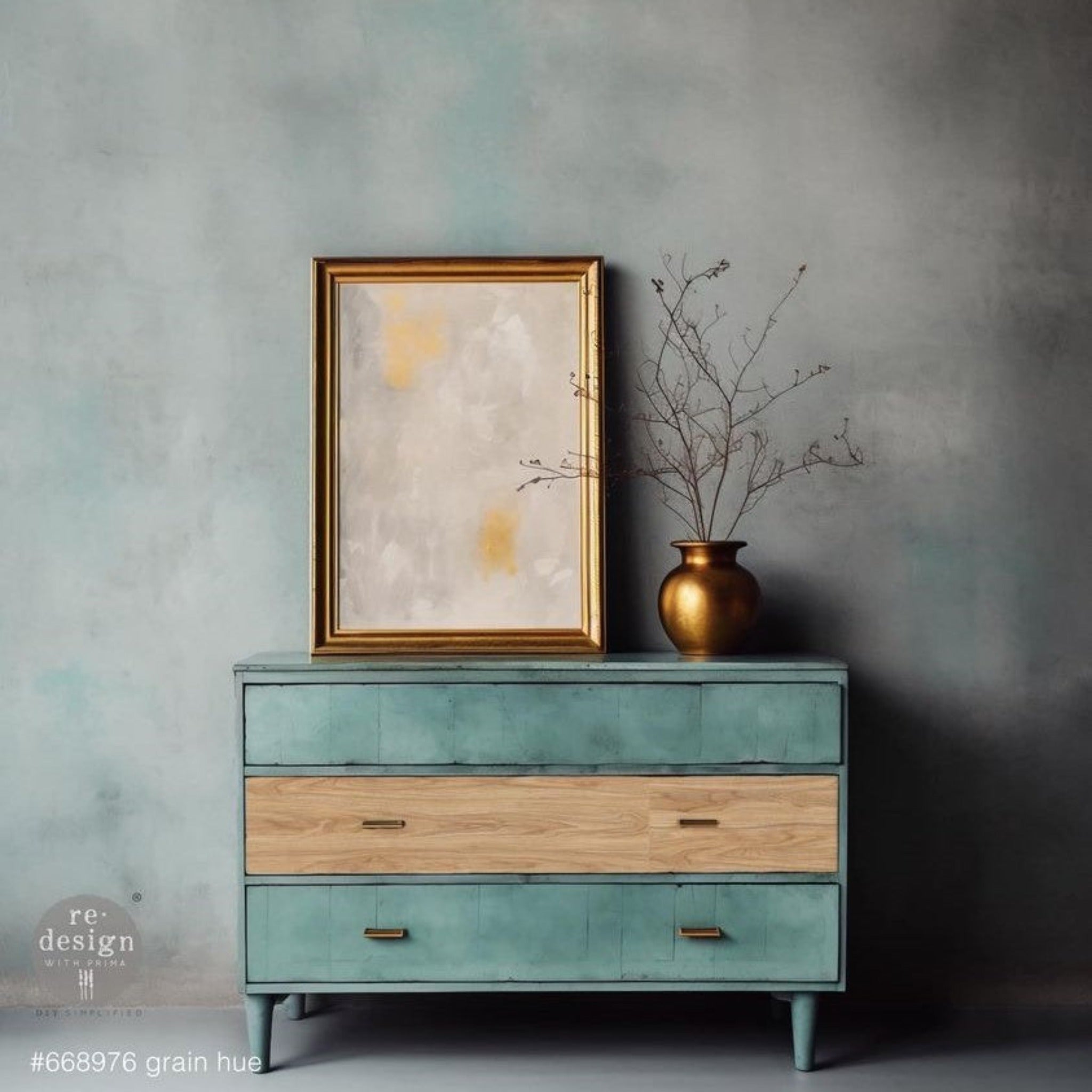 A mid-century 3-drawer dresser is painted light teal and features ReDesign with Prima's Grain Hue A1 fiber paper on the drawer in the middle.