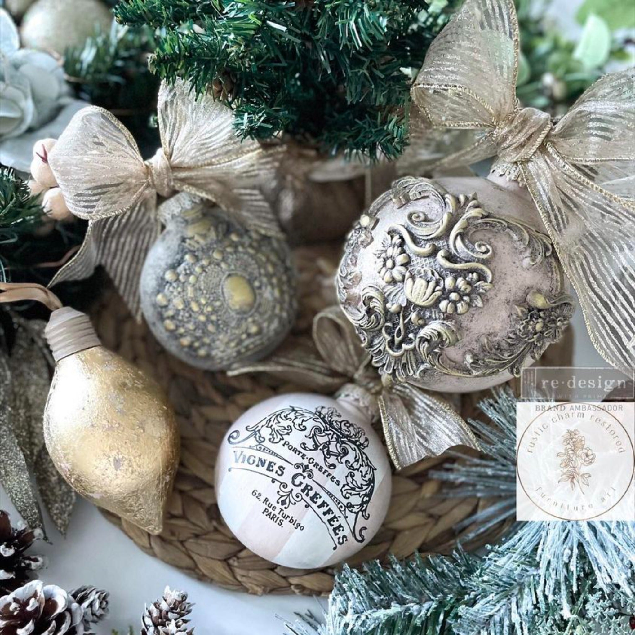 Four Christmas ornaments created by Rustic Charm Restored Furniture Art are painted beige, gold, and white. The white ornament features ReDesign with Prima's French Labels small transfer on it.