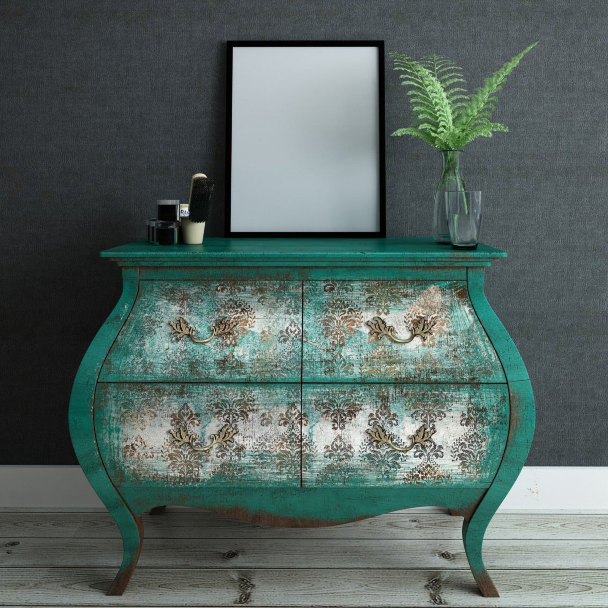 A vintage Bombay style dresser is painted distressed teal green and features ReDesign with Prima's Patina Flourish tissue paper on its 4 drawers.