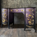 A vintage desk refurbished by The Grandson's Brush is painted eggplant purple with gold accents and features ReDesign with Prima's Kacha A Bird Song Gold Foil transfer on its drawers.