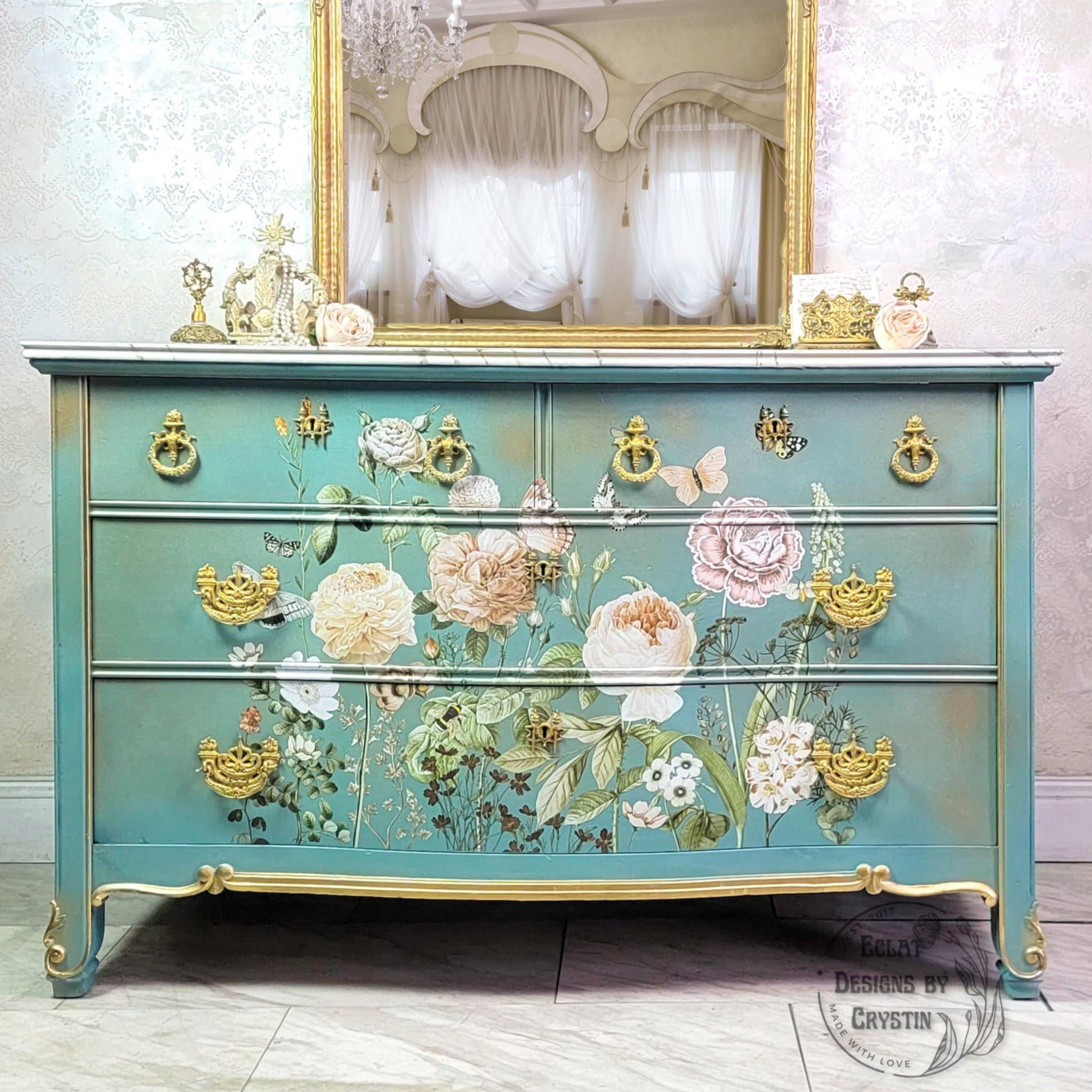 A vintage 4-drawer dresser refurbished by Eclat Designs by Crystin is painted light teal with gold accents and features ReDesign with Prima's All the Flowers transfer on its drawers.