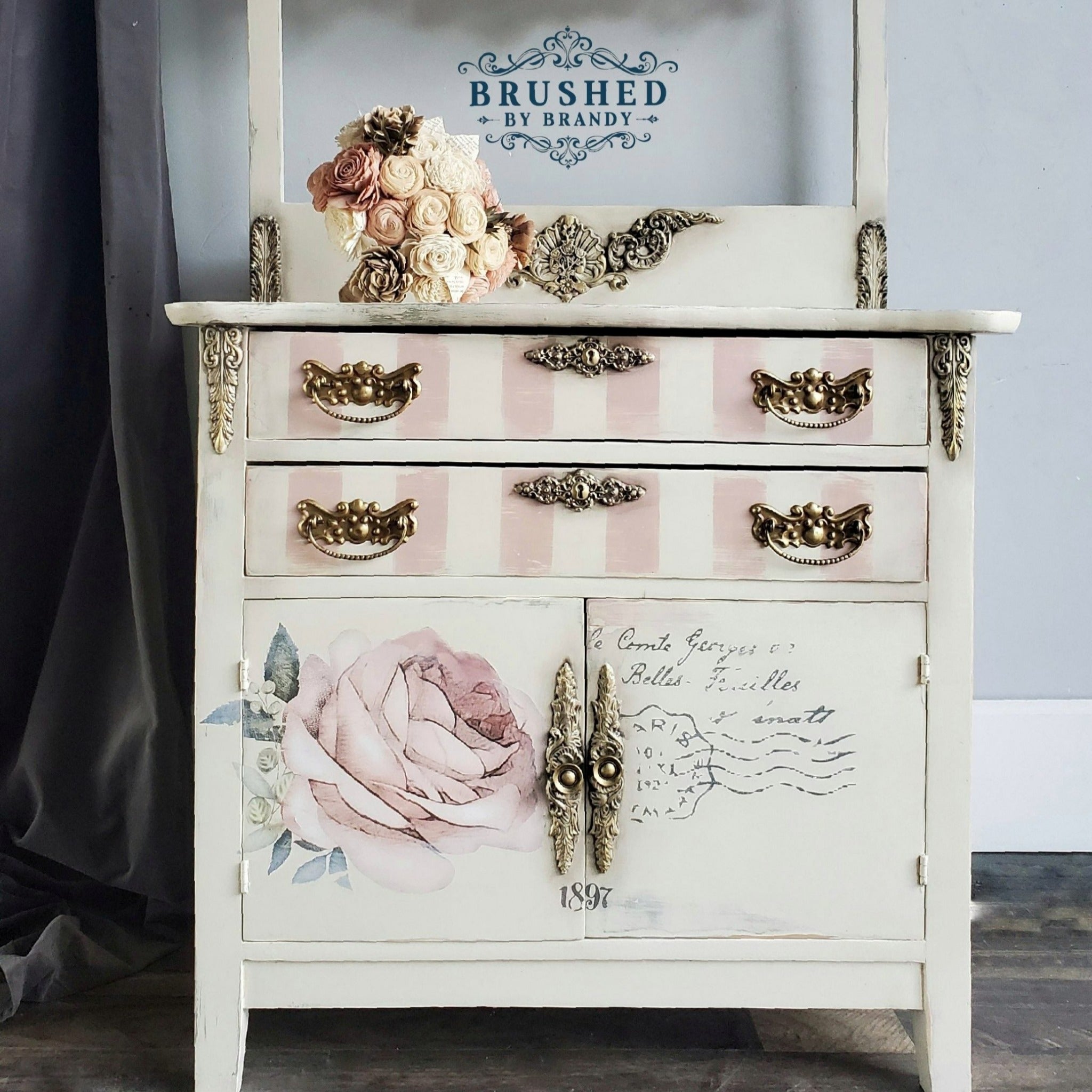 A vintage small buffet table refurbished by Brushed by Brandy is painted a cream white and features the Chatellerault transfer on its drawers.