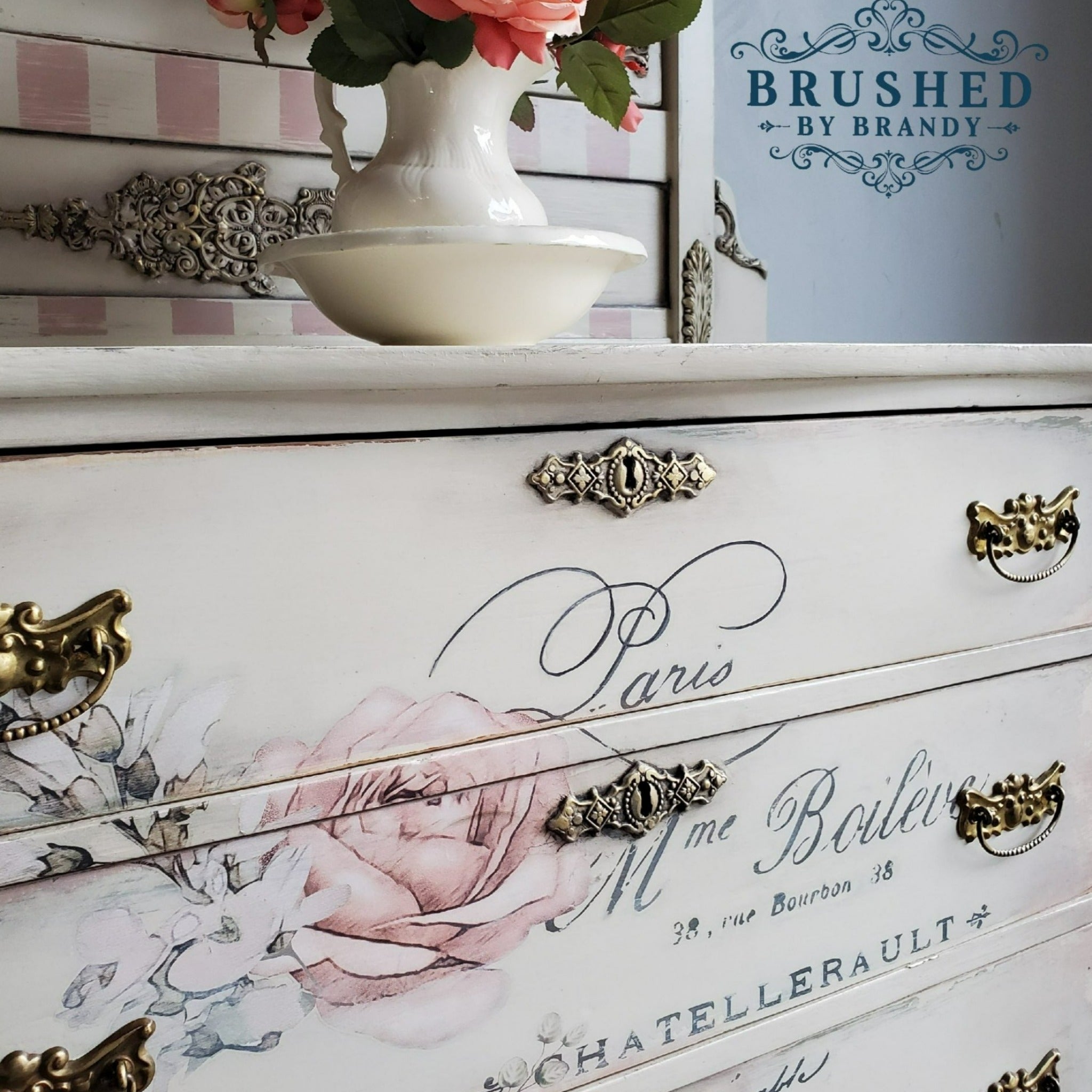 A close-up of a vintage small buffet table refurbished by Brushed by Brandy is painted a cream white and features the Chatellerault transfer on its drawers.