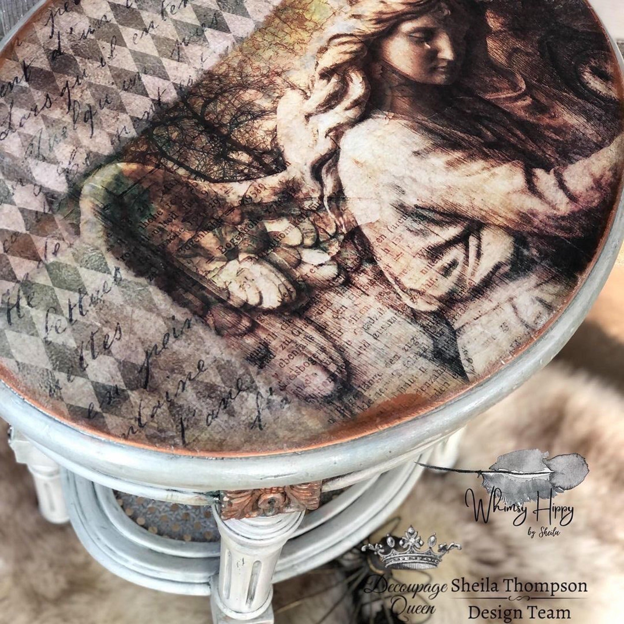 A close-up arial view of a vintage round side table refurbished by Whimsy Hippy by Sheila is painted light grey and features Decoupage Queen's Neutral Harlequin rice paper on the table top. Decoupage Queen's Gothic Angel rice paper is also featured with Neutral Harlequin.