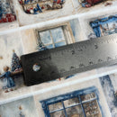 Close-up of decorative paper with Christmas-themed designs and a ruler for scale.