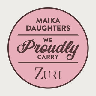 A white background with a pink circle with a brown outline and brown text reading: Maika Daughters. We proudly carry Zuri.