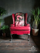 Red armchair with flamingo design in a room with plants and dark walls