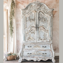 A vintage ornate armoire is painted light grey and feautres ReDesign with Prima's Alaina Toile transfer on it.