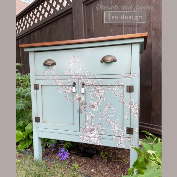 A vintage small buffet table refurbished by Dressers and Jujubes is painted pale blue and features ReDesign with Prima's Alaina Toile transfer on it.