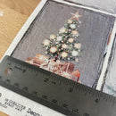 Christmas tree and presents on a textured paper with a ruler for scale.