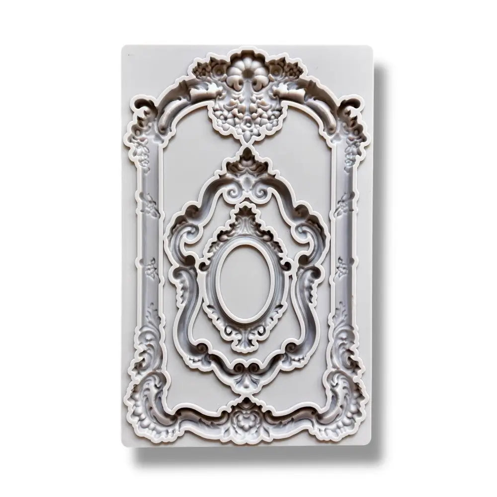 A light grey silicone mold featuring 3 intricately detailed baroque flourish frames is against a white background.