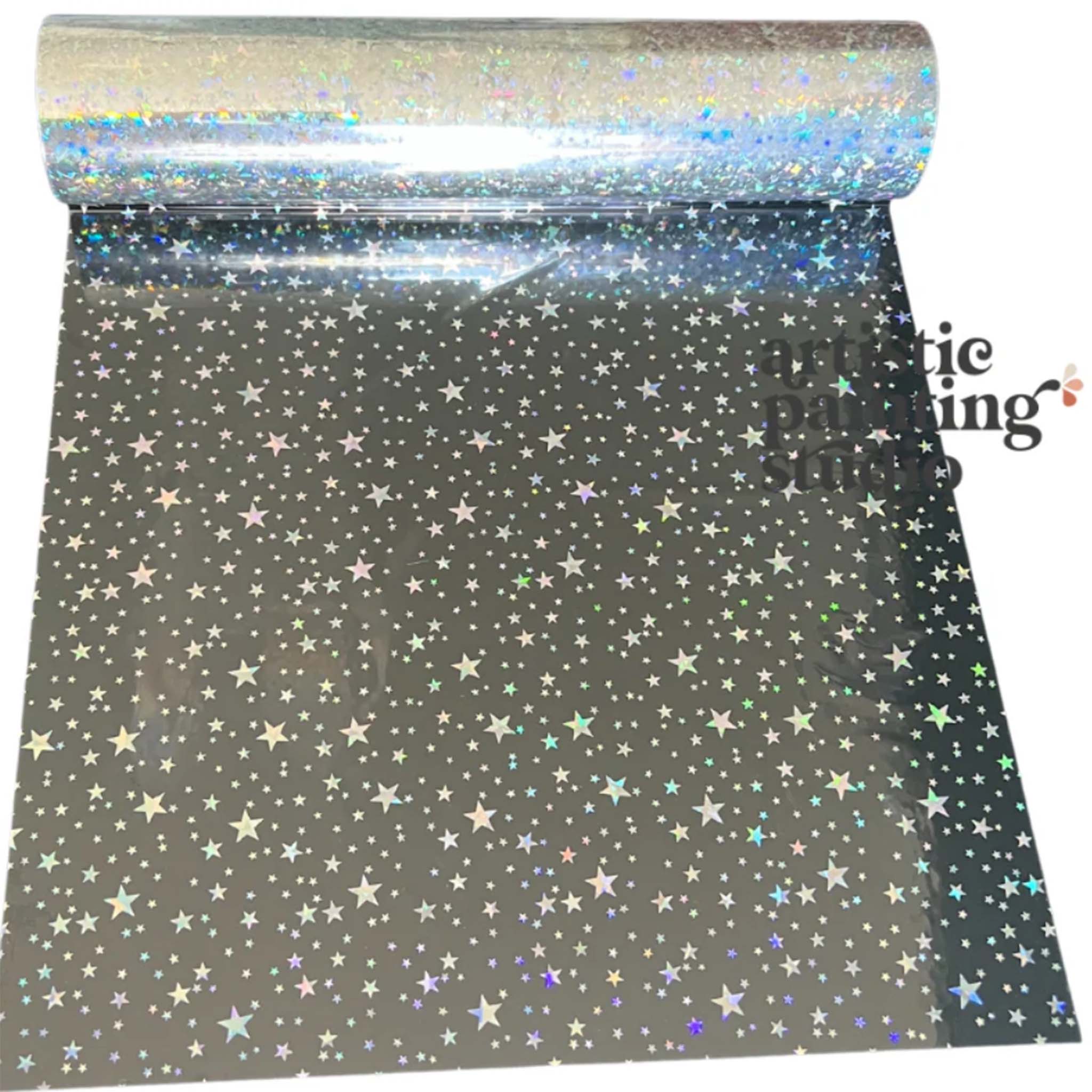 A roll of a silver holographic foil transfer that features an array of stars is against a white background.