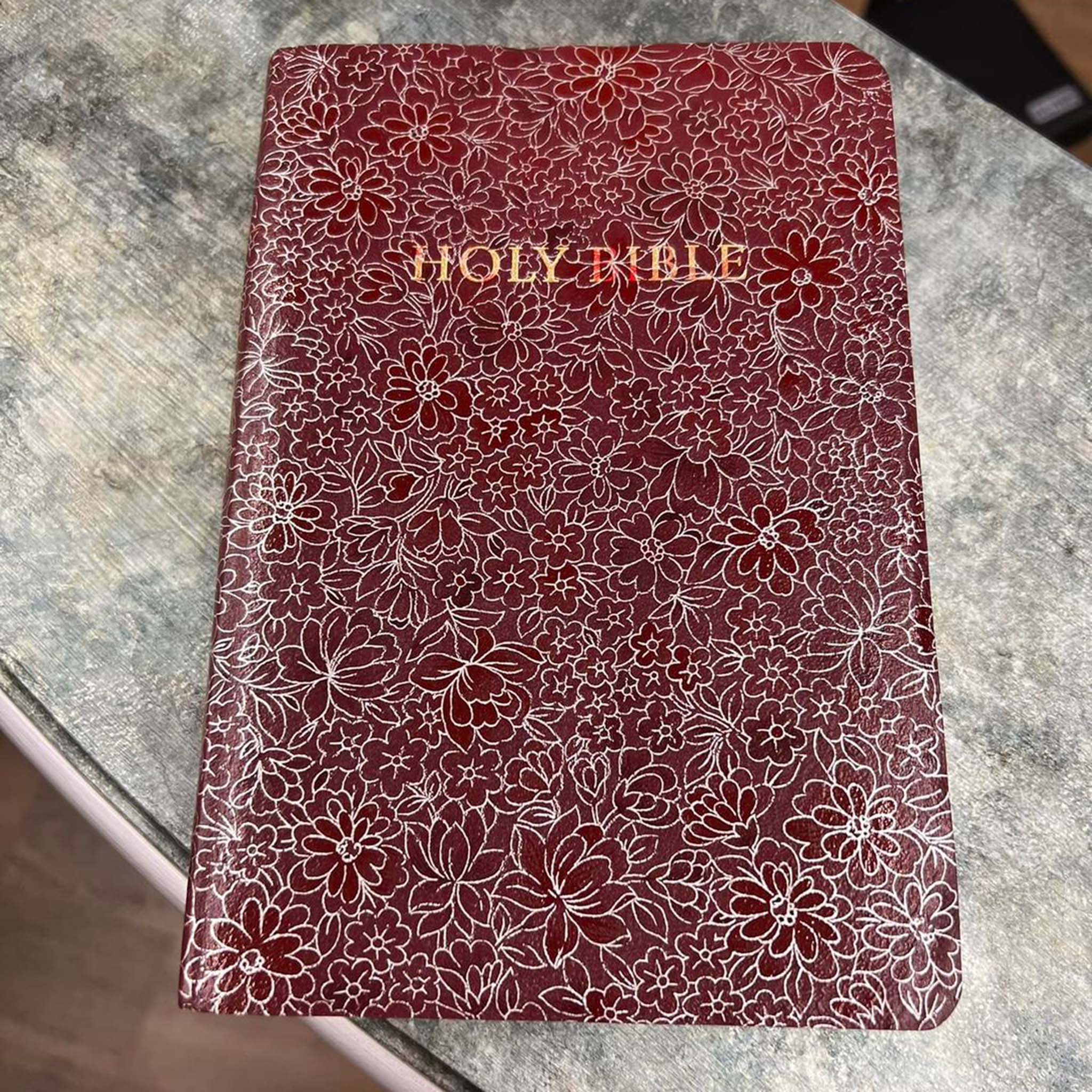 A red leather bound Holy Bible features Artistic Painting Studio's Ayva's Flowers metallic transfer foil on it.