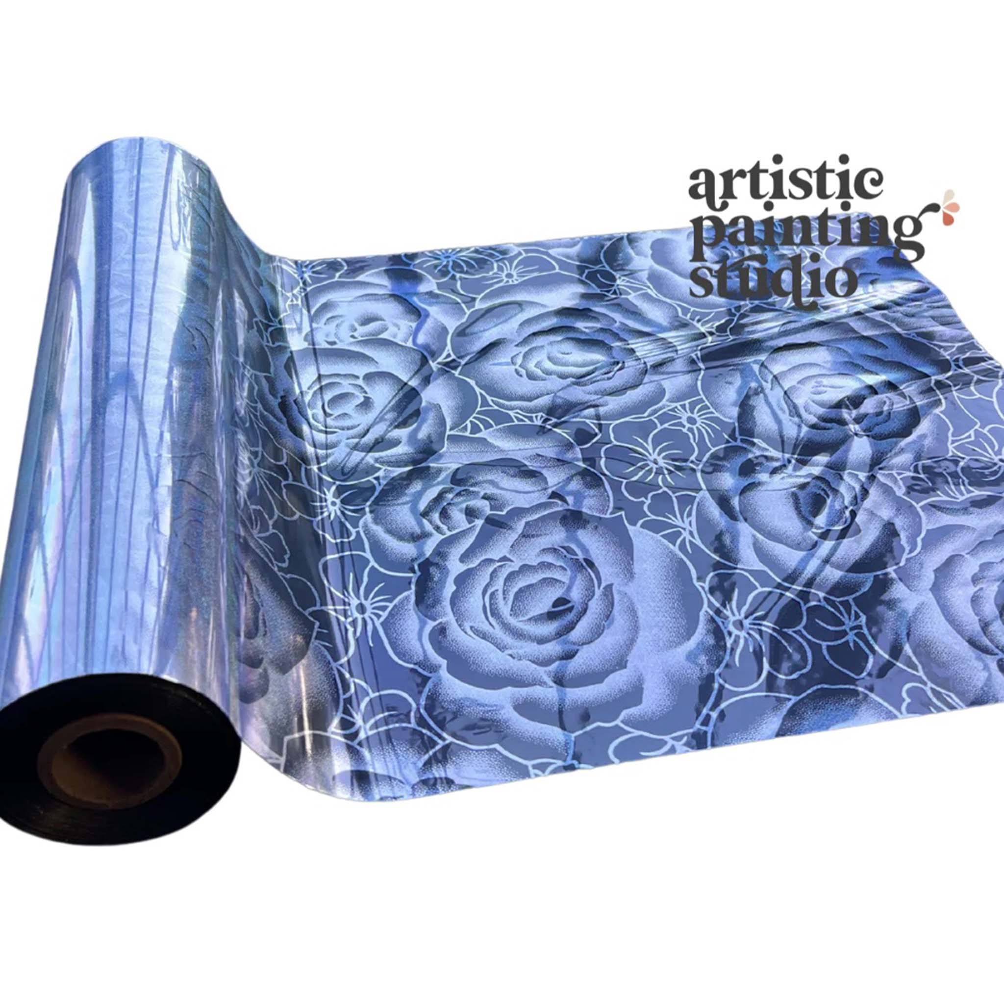 A roll of a holographic silver metallic transfer foil that features rose and flower blooms is against a white background.