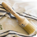 Dixie Belle Paint's Best Dang Brush is against a white hand towel with black stripes.