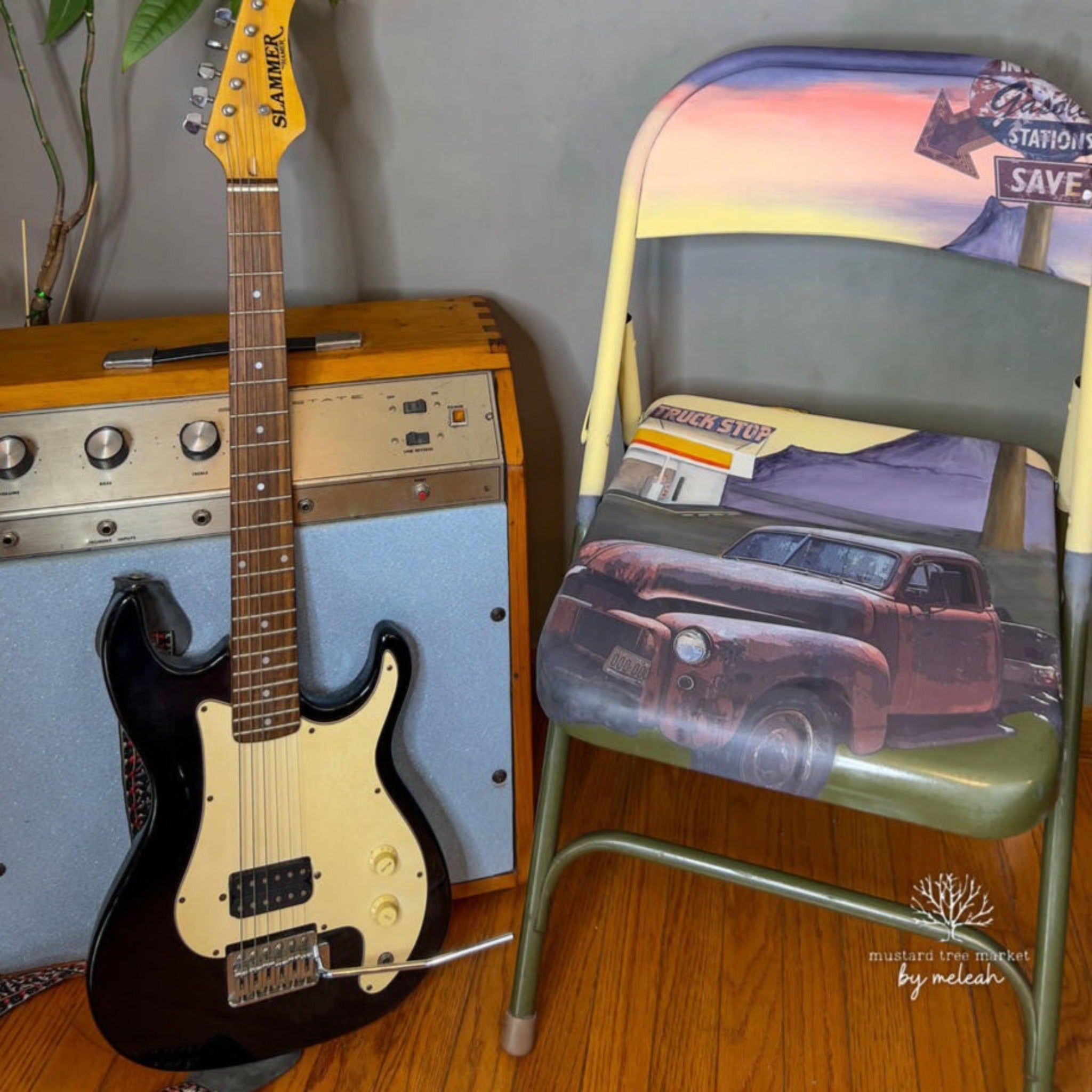 A metal folding chair is painted with a pastel Route 66 style design and features Belles & Whistles' Rusty Truck rub-on transfers on it. A vintage guitar and amp are next to the chair.