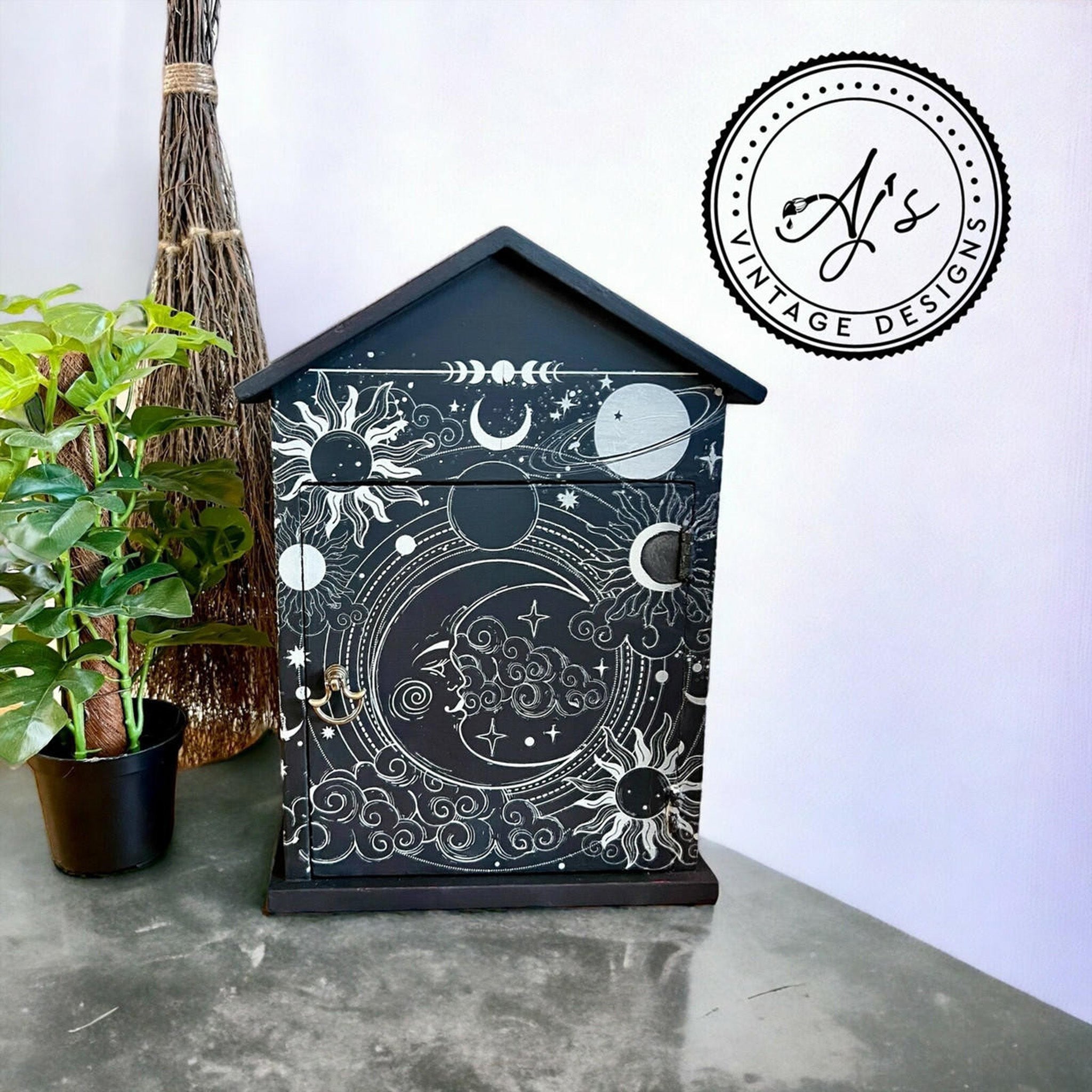 A small house shaped box created by AJ's Vintage Designs is painted dark blue and features Belles & Whistles' Lunar Solstice small rub-on transfer on it.