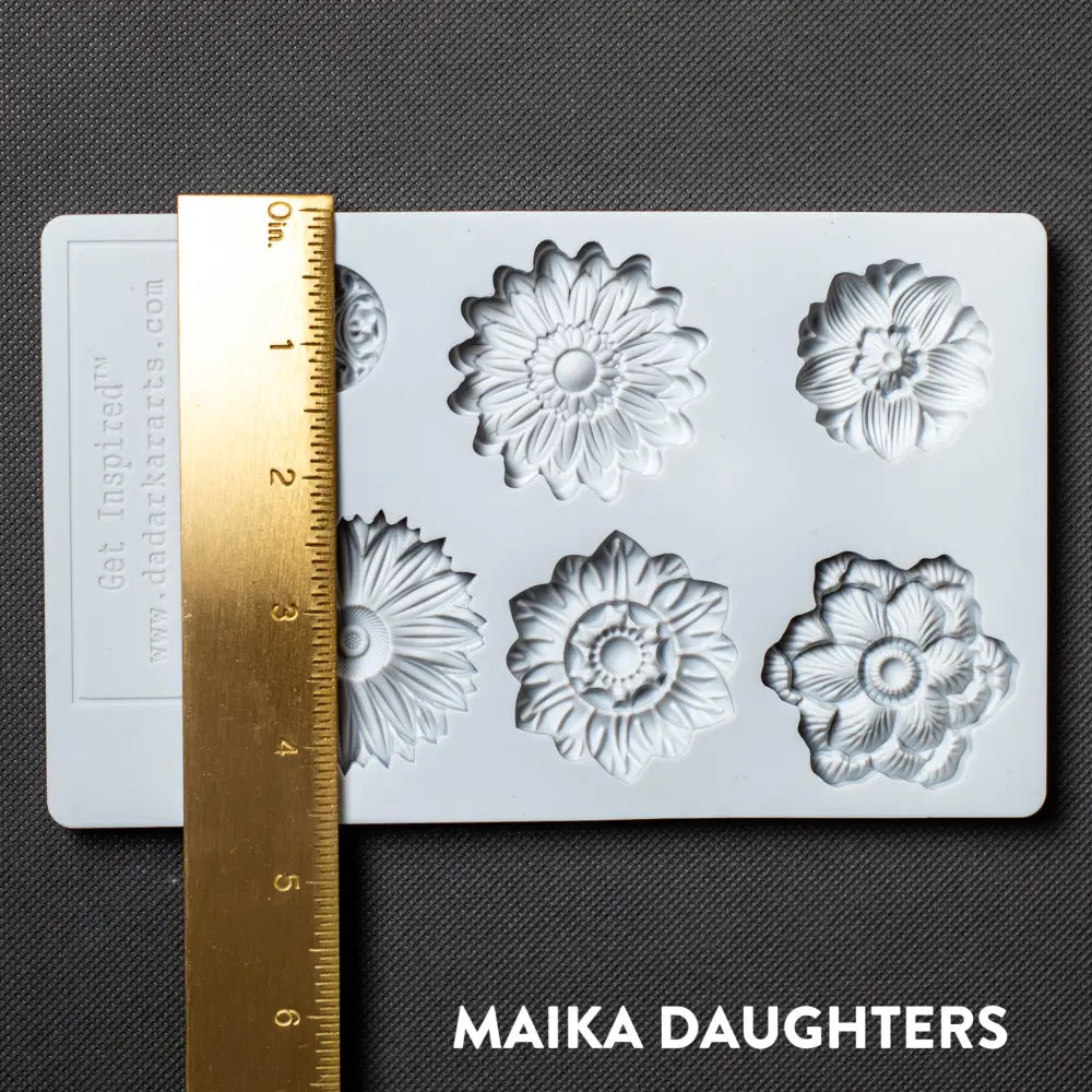 A light grey silicone mold featuring 6 posy flower heads is against a dark grey material background. A gold ruler reading 4.5" height sits on the mold.