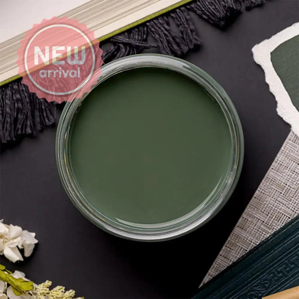 An arial view of an open container of Dixie Belle Paint Company's Blue Grass Chalk Mineral Paint is on a black table with other items.