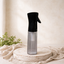 10 oz continuous fine mist spray bottle with black top and clear bottle displayed on a neutral studio pedestal.