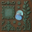 An open container of Dadarkar Art's Emerald Patina Metallic Wax Mousse is amongst resin silicone mold castings of a vintage square frame and various corner and accent rose flourishes.