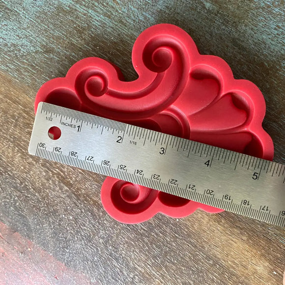 Red decorative silicone mold with a ruler for scale on a wooden surface