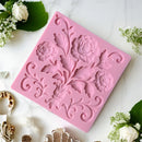 Pink floral silicone mold on a white surface with decorative elements.