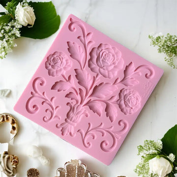 Pink floral silicone mold on a white surface with decorative elements.